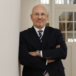 Matthias Grimm lehnt an einer Wand und lächelt